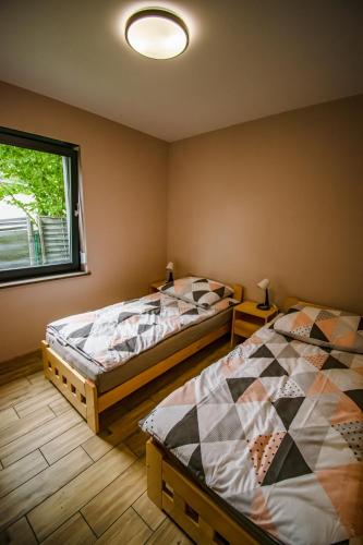 a bedroom with two beds and a window at Dębowa Przystań in Boszkowo-Letnisko