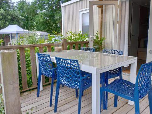 une table blanche et des chaises bleues sur une terrasse dans l'établissement Mobil home en Bretagne sud, à Guérande