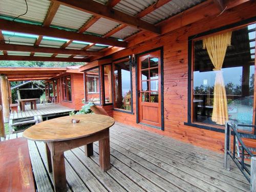 a wooden porch with a wooden table on a deck at Cabaña El Ulmo in Puerto Rico