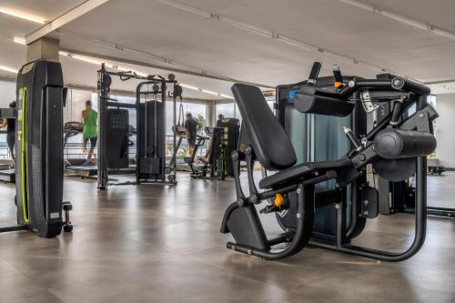 einen Fitnessraum mit Kardiogeräten und Personen im Hintergrund in der Unterkunft Brasília - Lakeside Apartamento in Brasilia