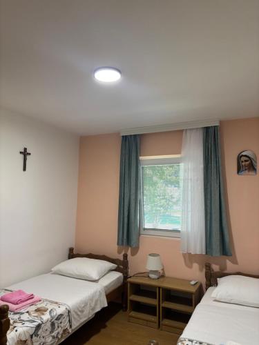 a bedroom with two beds and a window with a cross on it at Casa Del Pellegrino M&A - Ostojići in Međugorje