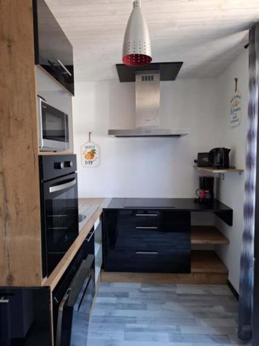 - une cuisine avec des armoires noires et une cuisinière noire dans l'établissement le nid des choups esprit loft 50 m2, à La Bourboule