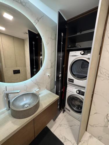 a bathroom with a sink and a washing machine at Harley Quinn Apartment in Poprad