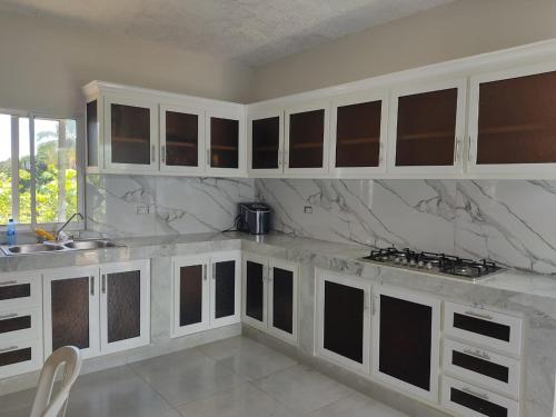 a kitchen with white cabinets and marble counter tops at Hermosa Casa en Juana Vicenta Samana in Santa Bárbara de Samaná
