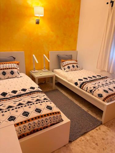 two twin beds in a room with yellow walls at La Casa del Trafalgar in Los Caños de Meca