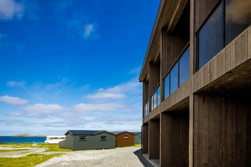 a building with glass windows next to the ocean at Arctic Apartments - Ramberg Beach in Ramberg