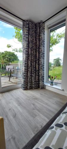 a living room with large windows and a patio at Bayview Lodge New Spacious Apartment in Breakish