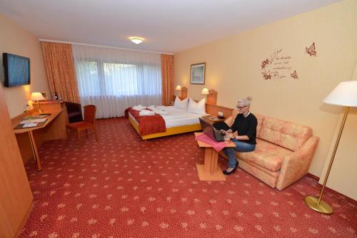 a man sitting on a couch in a hotel room at Hotel Die Kleine Blume in Erfweiler