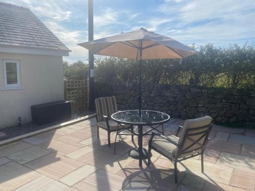 a table and chairs with an umbrella on a patio at Swallow Bach in Llanddyfnan