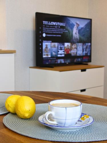 a cup of coffee and lemons on a table with a television at Apartament Studio 208 in Biała Podlaska