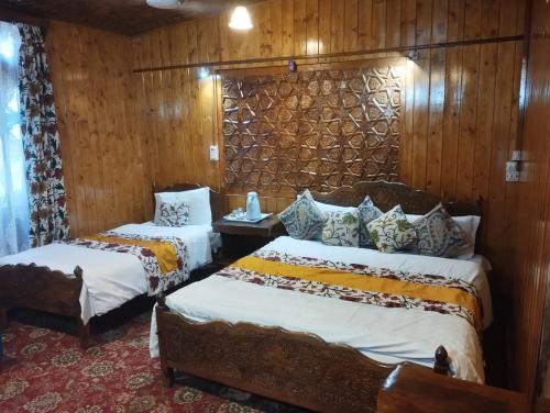 two beds in a room with wooden walls at Honolulu Group Of Houseboats in Srinagar