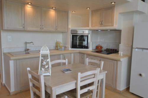a kitchen with a wooden table and a white refrigerator at Kathara Bay Apartments in Faliraki