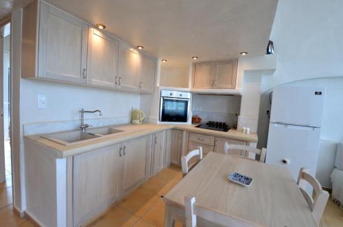 a kitchen with a sink and a table and a refrigerator at Kathara Bay Apartments in Faliraki
