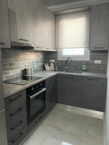a kitchen with gray cabinets and a sink and a stove at Modern & Charming Mitilini in Mytilene