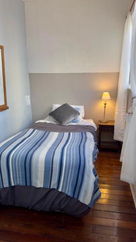 a bed with a striped blanket in a bedroom at BbCasita Yellow in Valparaíso