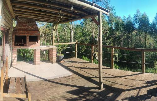 a wooden deck with a grill on top of a house at Cabana rustica logcabin com banheira aquecida in Osório