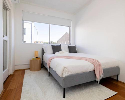 a bedroom with a large bed and a window at 1 min to the beach with A/C, balcony & parking in Sydney