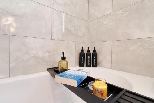 a bath tub with bottles and a book and candles at Cowpen Lodge in Stockton-on-Tees