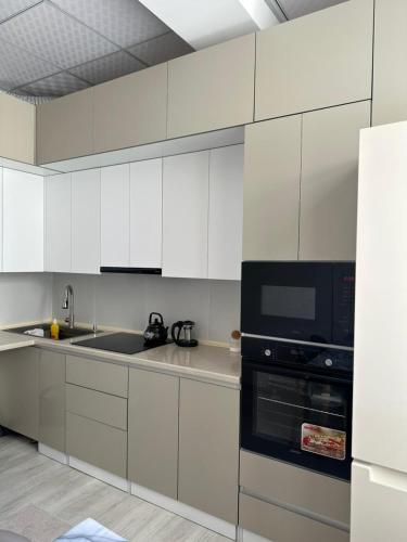 a kitchen with white cabinets and a black microwave at Pamir Tower Apartments in Khorog