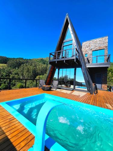 a house with a swimming pool on a wooden deck at Chalé Encantos do Frade in Bom Retiro
