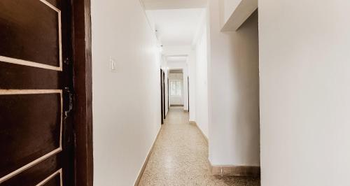 a hallway with white walls and a wooden door at Super Hotel O Sushma Lodge in Manipala