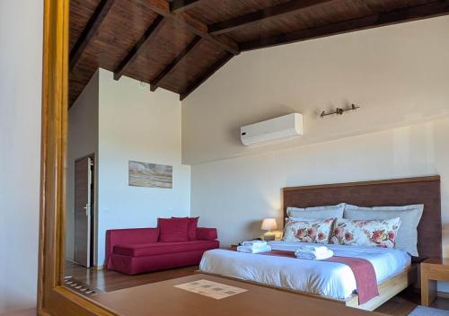 a bedroom with a large bed and a red chair at Althea Apartments in Katakolon
