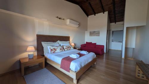 a bedroom with a large bed and a red chair at Althea Apartments in Katakolon