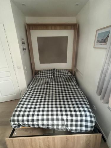 un lit avec un matelas à carreaux noirs et blancs dans une chambre dans l'établissement Charmant studio 1 neuf triangle d'or Deauville!, à Deauville