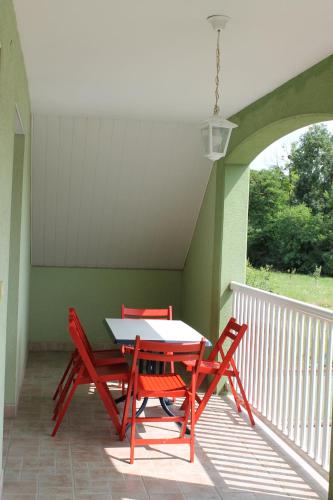 - deux chaises rouges et une table sur une terrasse couverte dans l'établissement Gite Rémy&Sylvia, à Obersaasheim