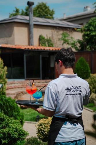 a man holding a tray with two cocktails on it at Boutique Hotel Kviria in Tʼelavi