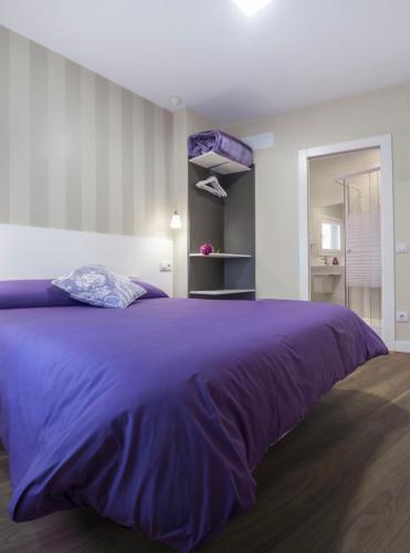a large purple bed in a white room at Pensión Entreviñas in Logroño