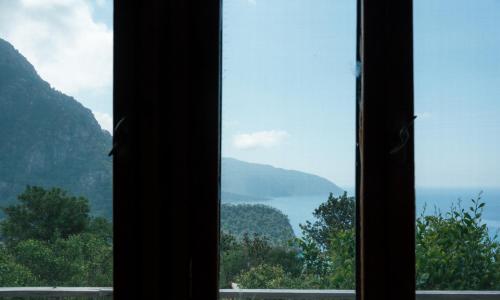 a window with a view of the ocean and mountains at Olive Garden Kabak in Faralya