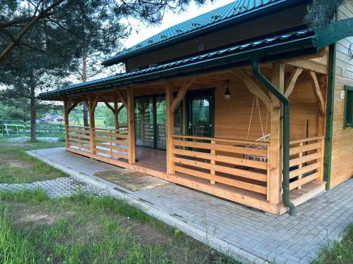 a wooden cabin with a porch on a patio at Farma Albert Korzenie in Pruchnik-Miasto