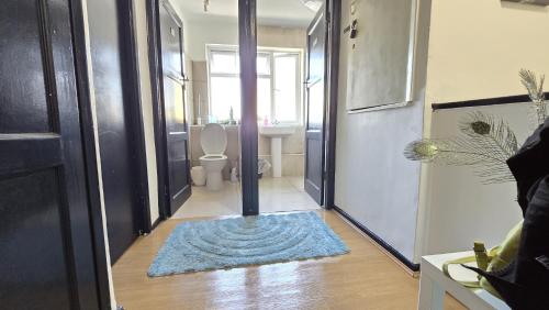 a hallway with a bathroom with a toilet and a rug at Canary wharf cottage in London