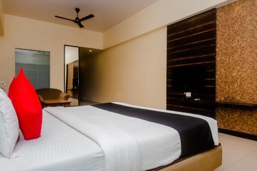 a bedroom with a large white bed with red pillows at Hotel O Sai Plaza in Kalyan