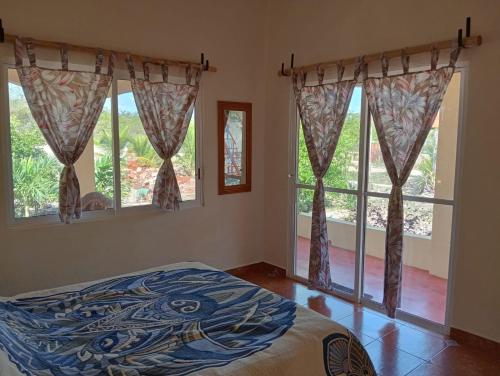 a bedroom with a bed and two windows at Rancho Camote - Frida 1 bedroom in Chichimilá