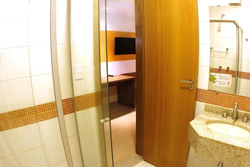 a bathroom with a sink and a glass shower door at Prive Thermas - OFICIAL in Caldas Novas