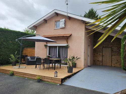 a patio with an umbrella and a table and chairs at Gîte & Chambres d'Hôtes - Le Petit Bali in Saint-Pandelon