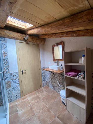 a bathroom with a toilet and a wooden ceiling at La Sabina in Terriente