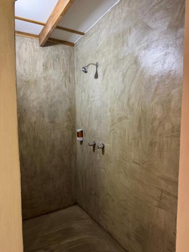 a shower in a bathroom with a stone wall at Passion Fruit Lodge in Cahuita