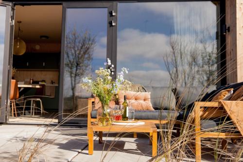 a patio with a couch and a table with flowers on it at Ecohome Golf 8pers and baby Zeezand Recreatie in 't Zand