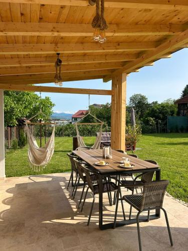 a table and chairs under a wooden pergola at Vila San Nicoara in Curtea de Argeş