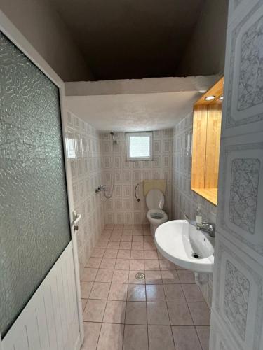 a bathroom with a toilet and a sink at Vila 23 in Dhërmi