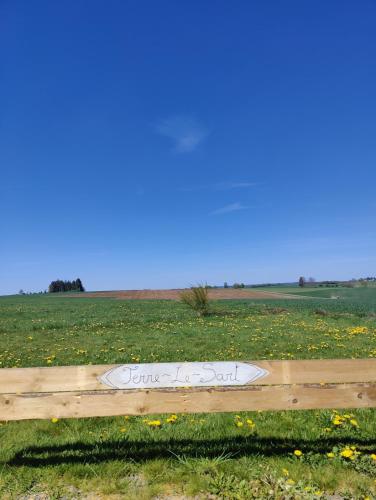 a sign on a wooden fence in a field at Terre - Le - Sart in Neufchâteau