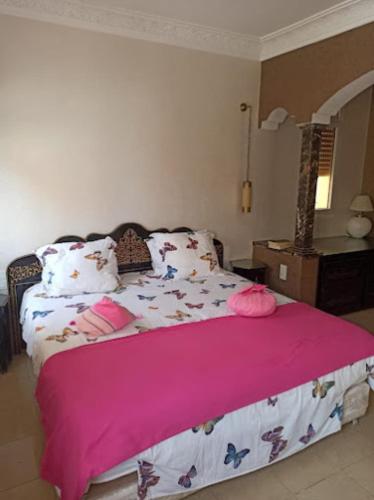a bedroom with a large bed with a pink blanket at Maison ASSIA in Zaouit Aglou