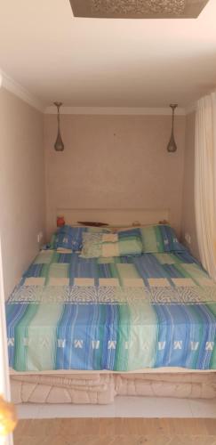a bedroom with a bed with blue and green sheets at Maison ASSIA in Zaouit Aglou