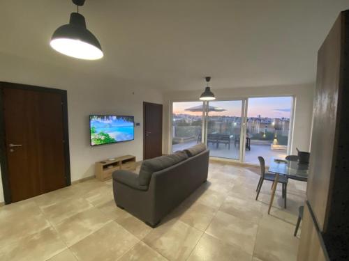 a living room with a couch and a tv and a table at Sailsbury in Msieraħ
