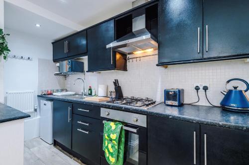 a kitchen with black cabinets and a stove top oven at Luxury 1 bedrooom house, sleeps 4, free parking in Queensbury
