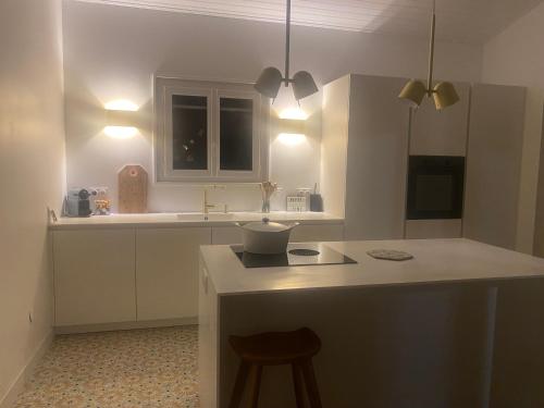 une cuisine avec des placards blancs et un comptoir avec un tabouret dans l'établissement Maison cabane proche océan/bassin !!!, à Lège-Cap-Ferret