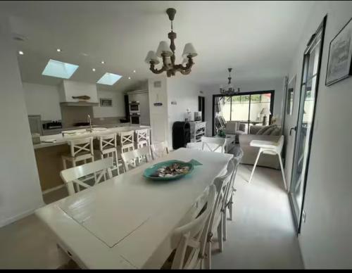 une cuisine et une salle à manger avec une table et des chaises blanches dans l'établissement Villa Les Lopins, à Arcachon